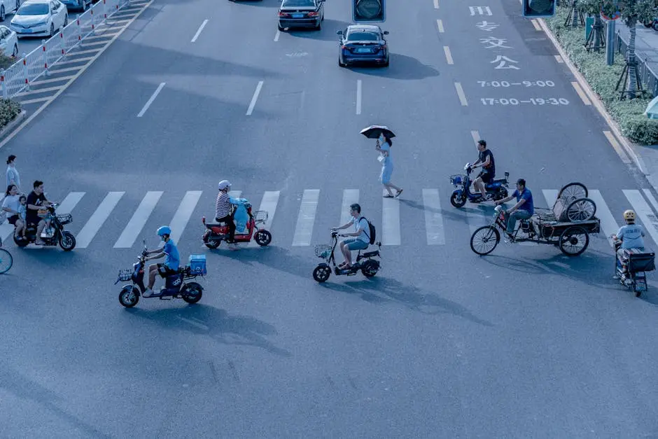 A bustling city intersection with scooters and pedestrians on a sunny day.