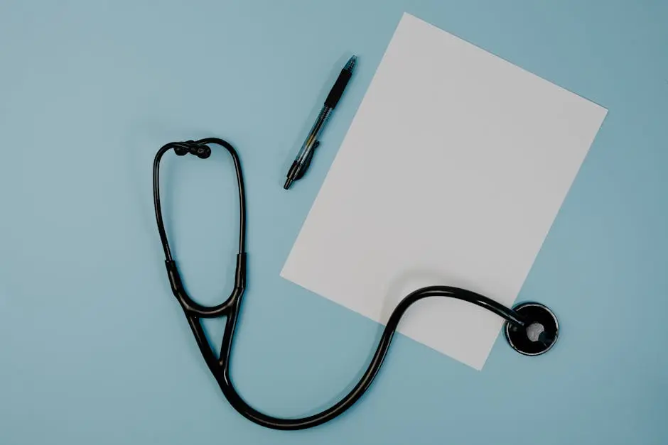 Flat lay of stethoscope, blank paper, and pen on blue surface, ideal for medical themes.