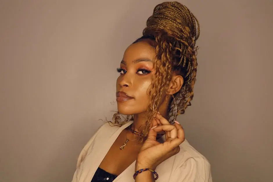 Portrait of a stylish woman with intricate braided updo and fashionable makeup in a studio setting.