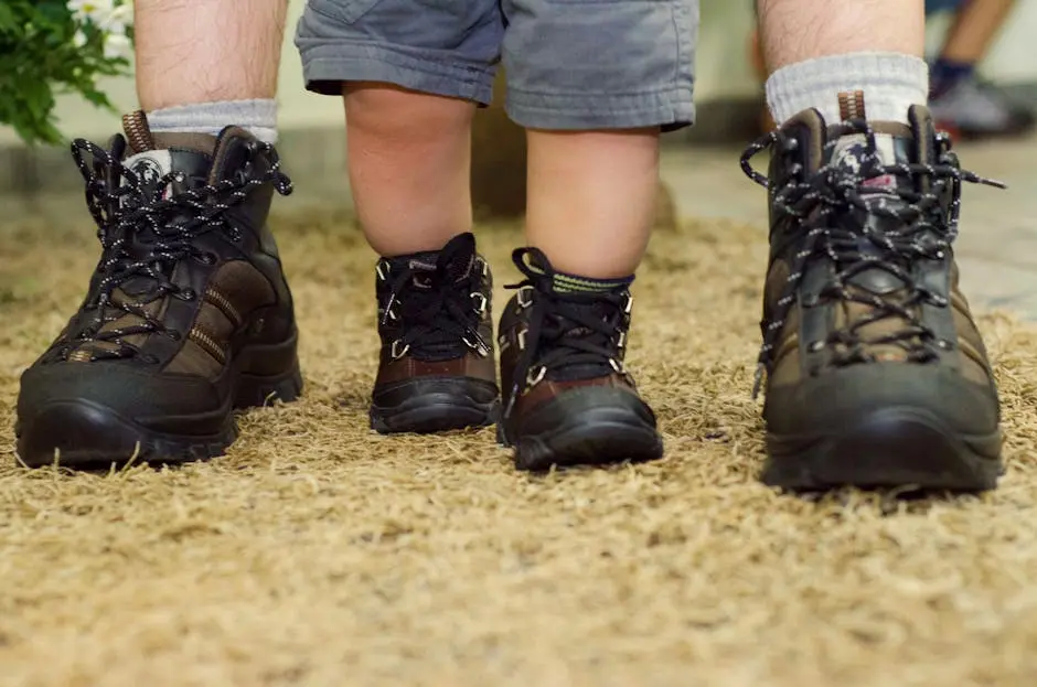 Close-up of a father and child’s hiking boots on a carpet, emphasizing family bonding and adventure.