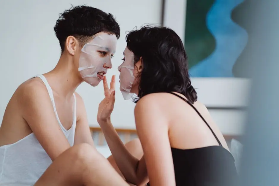 Intimate moment between two women applying sheet masks in a cozy indoor setting.