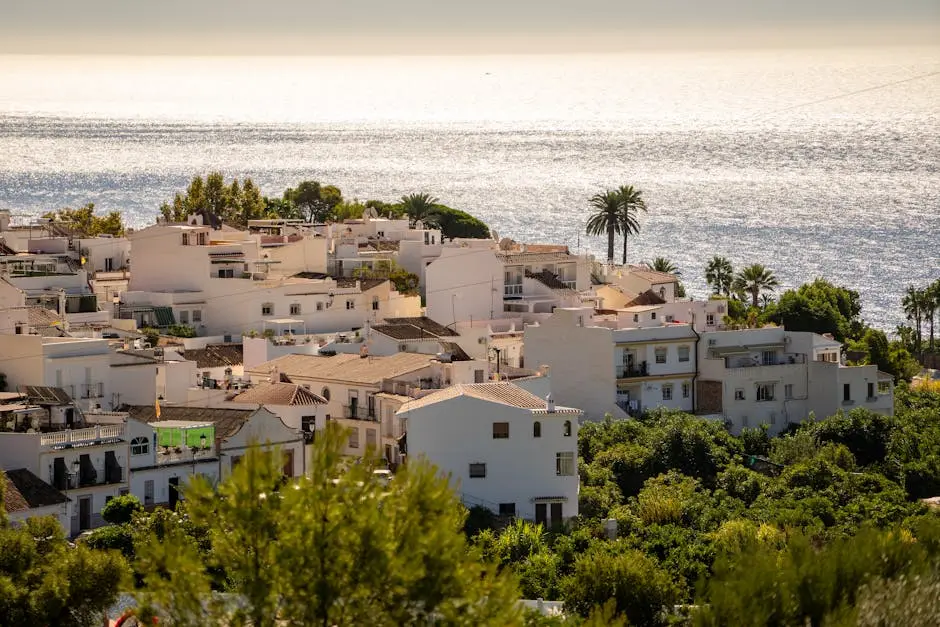 Tranquil view of Nerja’s white houses and the shimmering Mediterranean Sea under a bright summer sky.