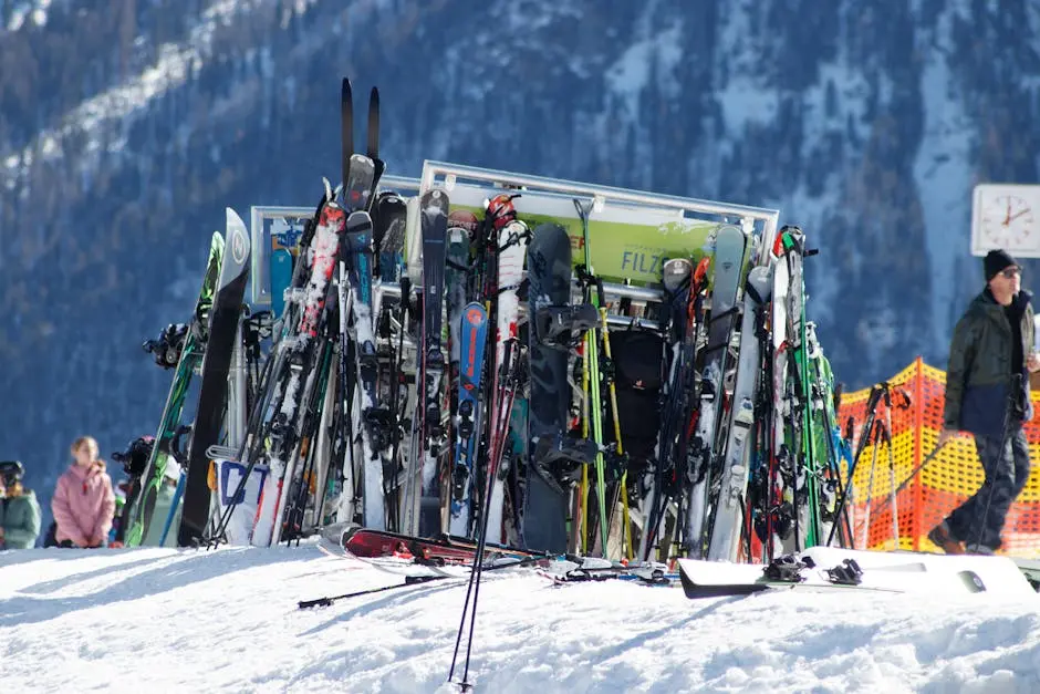 A collection of skis and snowboards in a snowy mountain resort setting. Winter adventure awaits.