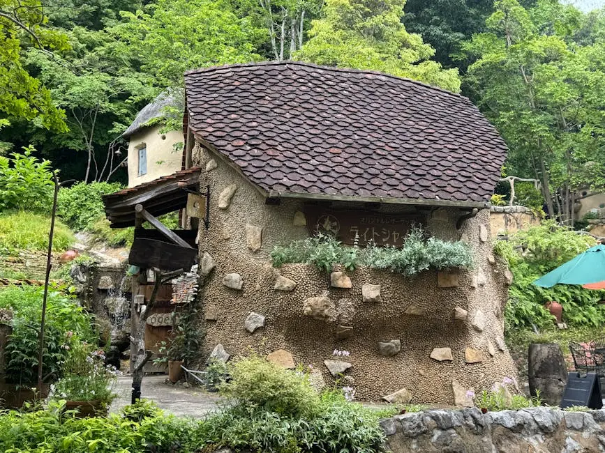 A charming rustic cafe with stone walls and a thatched roof nestled in a lush green forest.