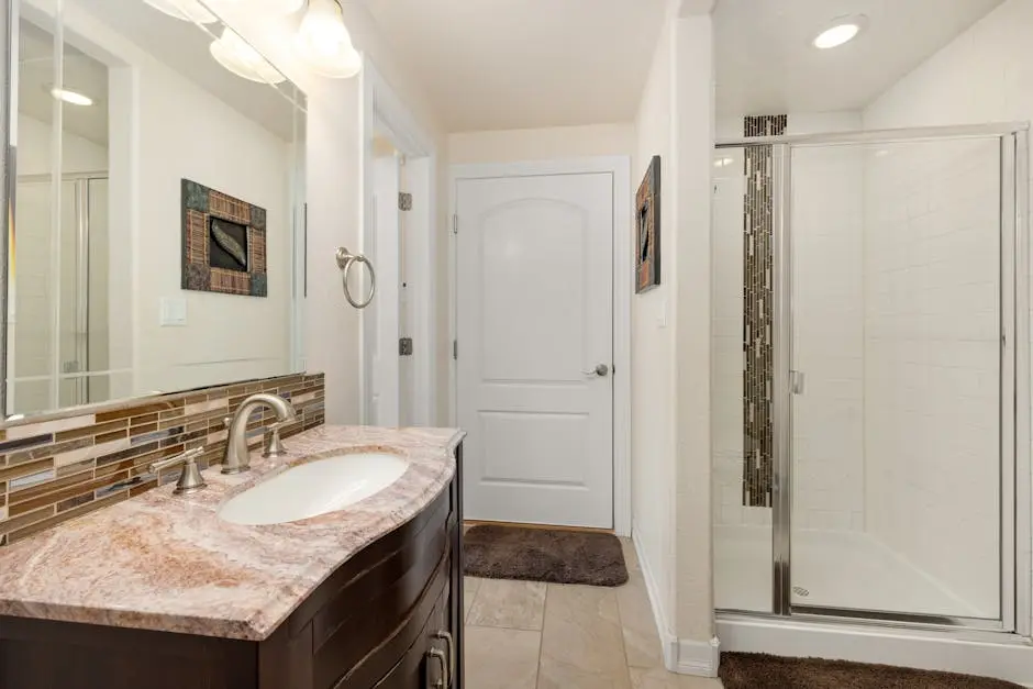 Contemporary bathroom design featuring granite sink countertop and glass shower enclosure.