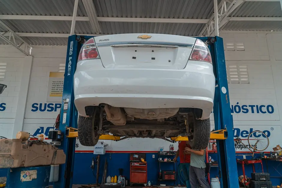 A white Chevrolet car is lifted for maintenance in an automotive repair shop.