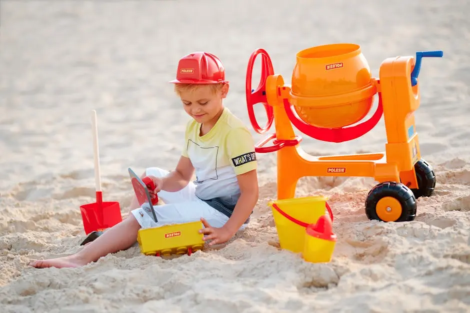 Young boy playing with toy cement mixer and tools in outdoor sandbox.