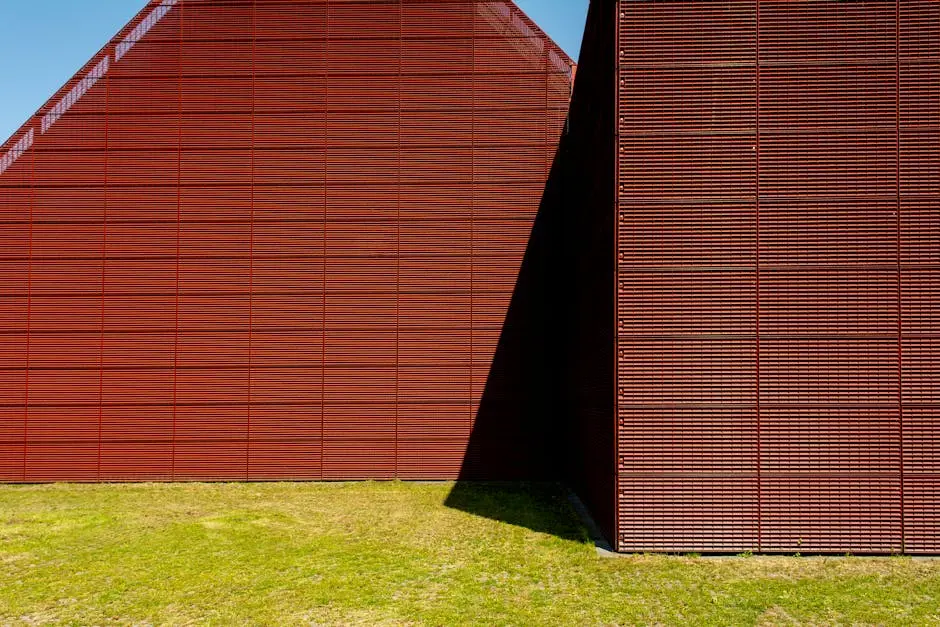 A vibrant red barn with a geometric facade in a rural setting under a clear blue sky.