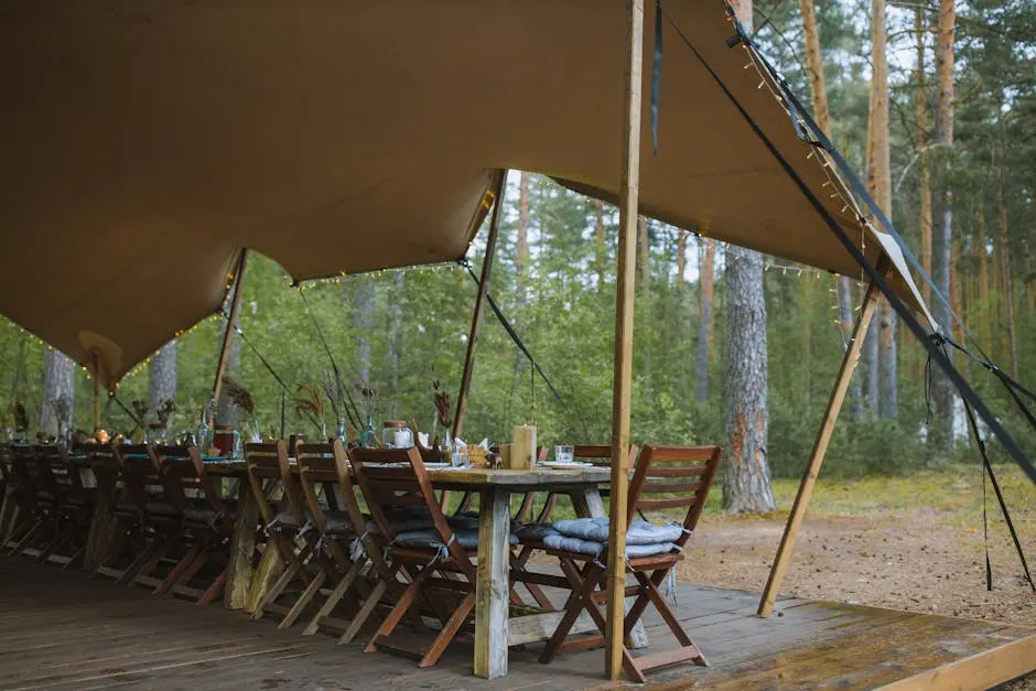 A cozy outdoor dining setup under a tent in a serene forest, ideal for gatherings.