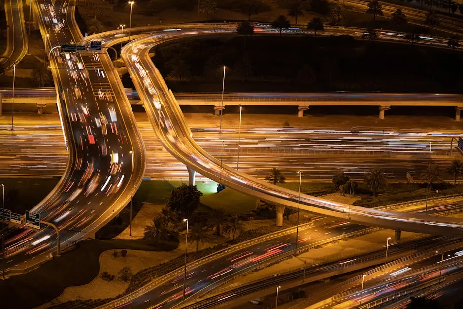 Aerial view of light trails on a busy Dubai highway interchange at night, showcasing vibrant city life.