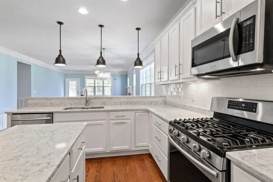 Sleek kitchen featuring stainless steel appliances and marble countertops under pendant lighting.