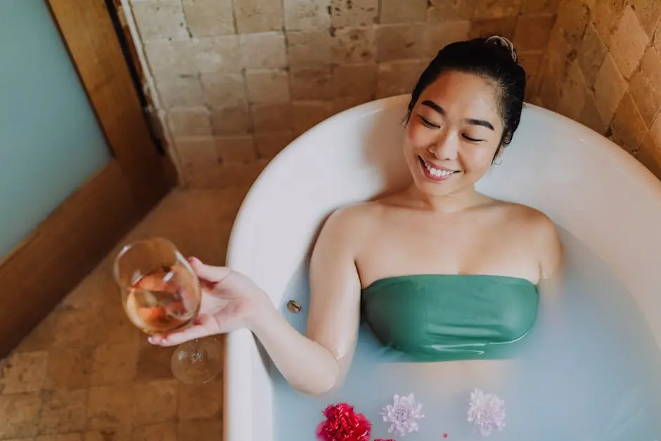 Asian woman enjoying a relaxing bath with wine and flowers, embodying spa-like wellness and tranquility.