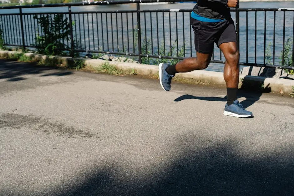 Athletic man running along a riverside path, promoting healthy living and exercise outdoors.