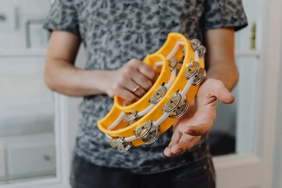 A musician holding and playing a vibrant yellow tambourine indoors.