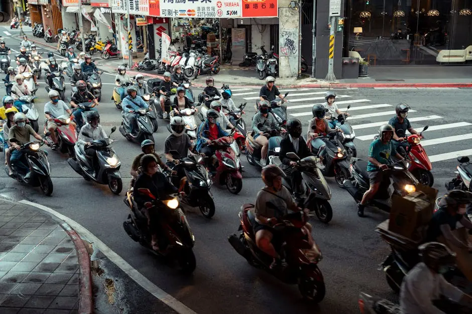 A bustling urban intersection filled with scooters and diverse riders in a city street scene.