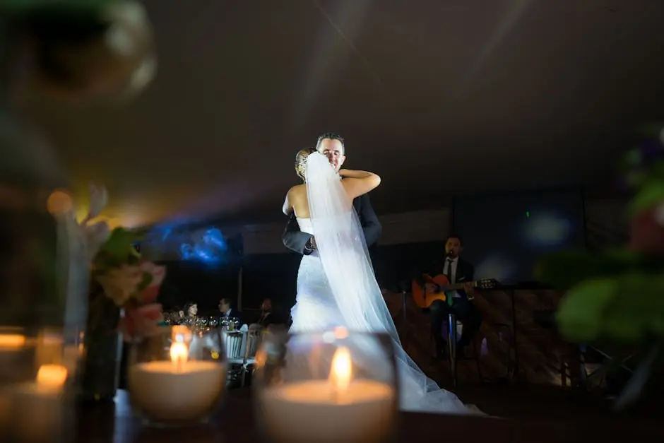 Romantic wedding dance scene with bride and groom embraced, surrounded by candles and live music.