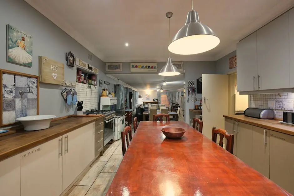 Warm and inviting kitchen with a long wooden table and pendant lights.