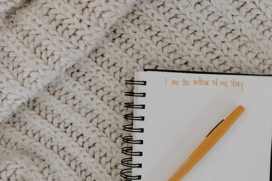A notebook with motivational writing and pen on a knit blanket flatlay.