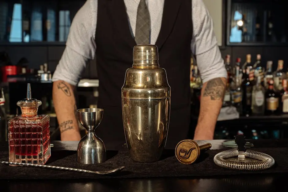 A bartender’s setup featuring a cocktail shaker and bar tools on a counter, ready for mixing.