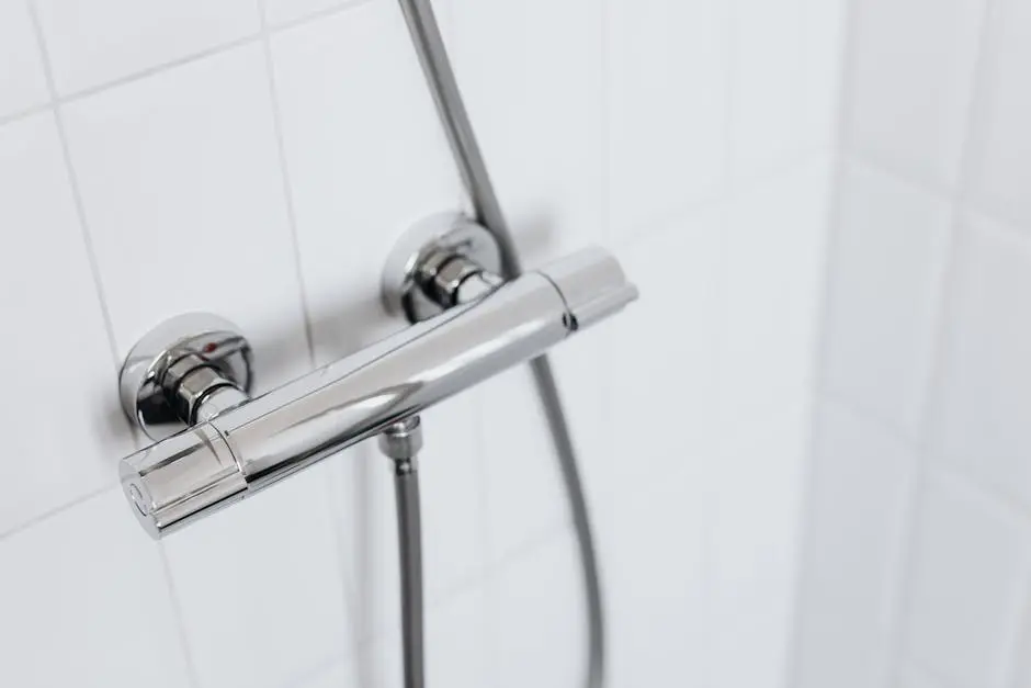 Modern chrome shower faucet on white tiled wall, elegant and clean design.