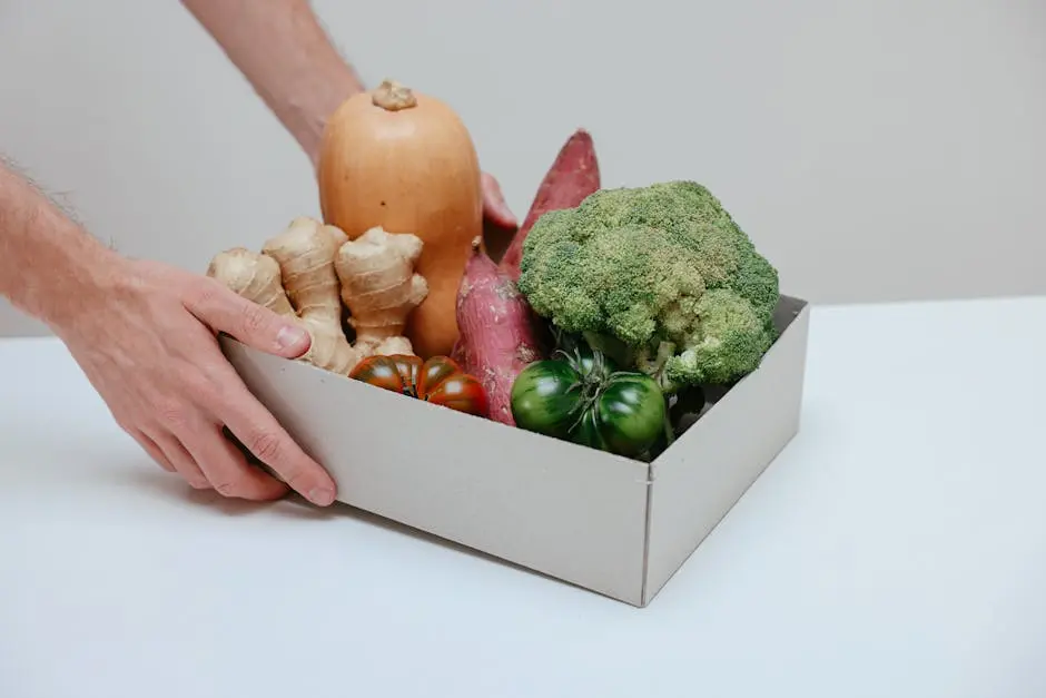 A cardboard box filled with fresh organic vegetables, being lifted by hands.