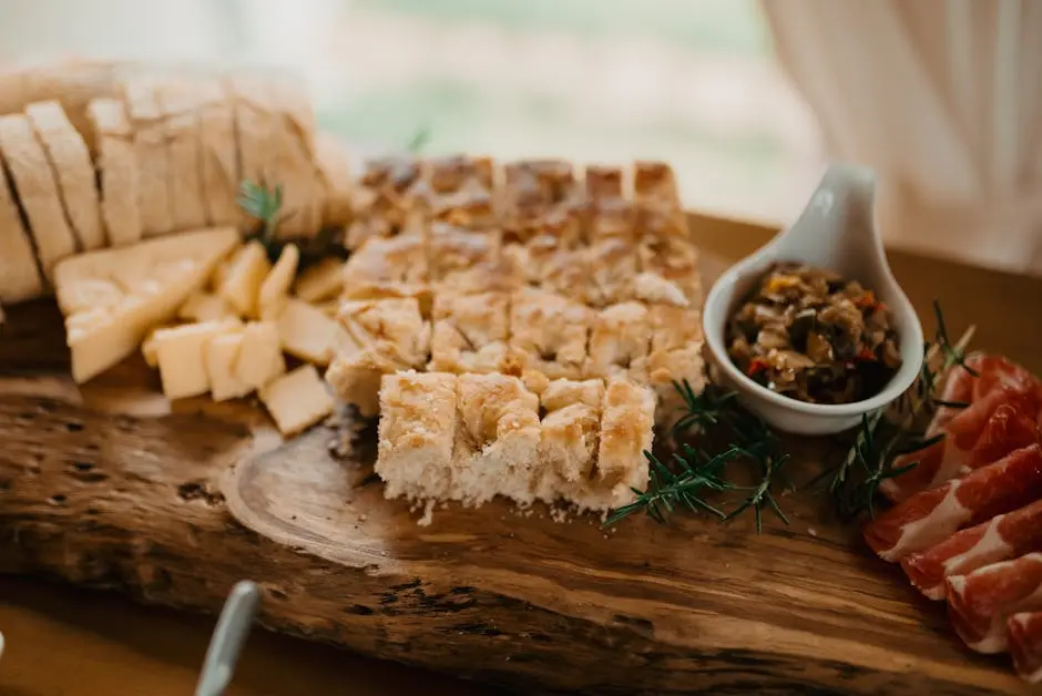 Rustic antipasto platter featuring focaccia, cheese, charcuterie, and olives on a wooden board.