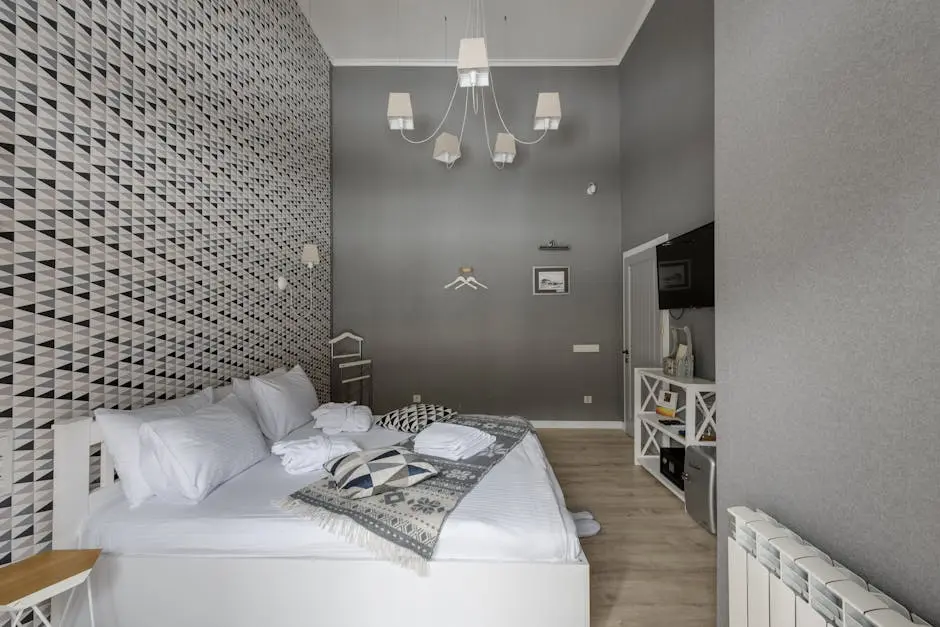 Stylish hotel bedroom with modern decor, featuring a comfortable bed and geometric wallpaper.