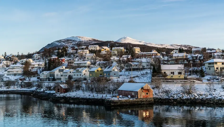 A picturesque Norwegian village with snow-covered houses and a waterfront view, showcasing winter scenery.