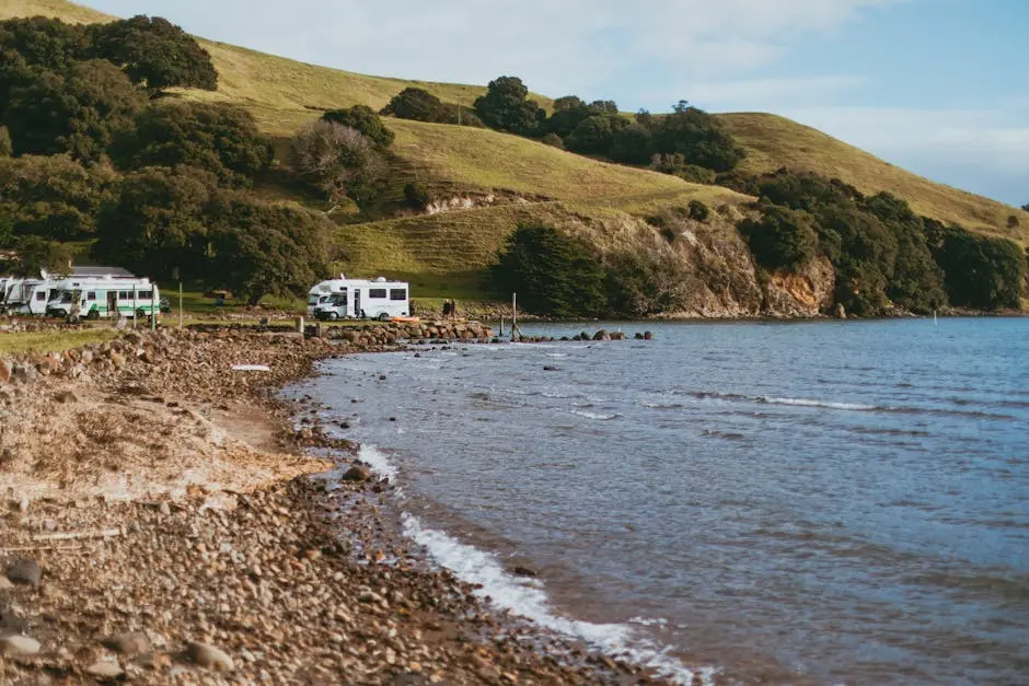 Tranquil campsite along the Coromandel coast with lush hills, trees, and sea views.