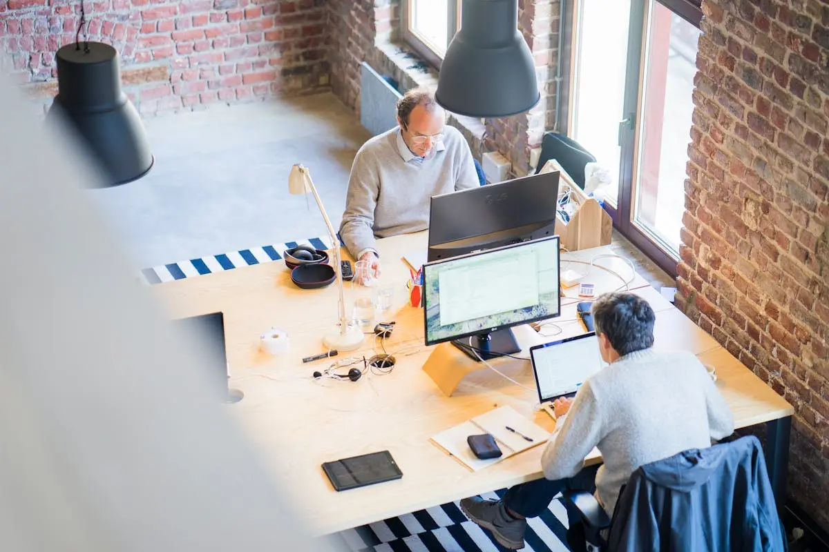 Bird’s-eye view of a modern office with professionals collaborating on laptops and monitors.