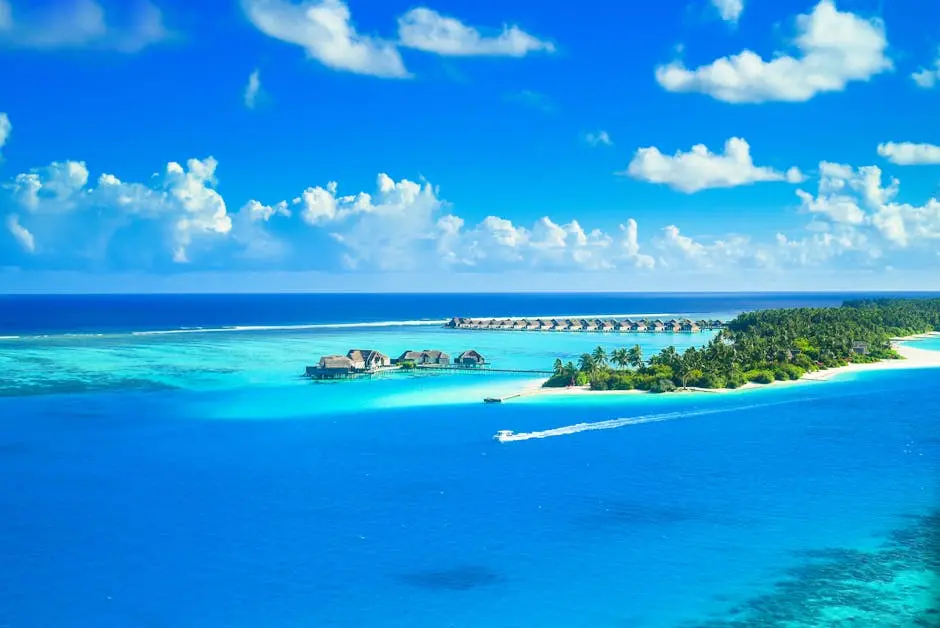 Aerial view of a luxurious tropical resort on a pristine island surrounded by azure waters and lush greenery.
