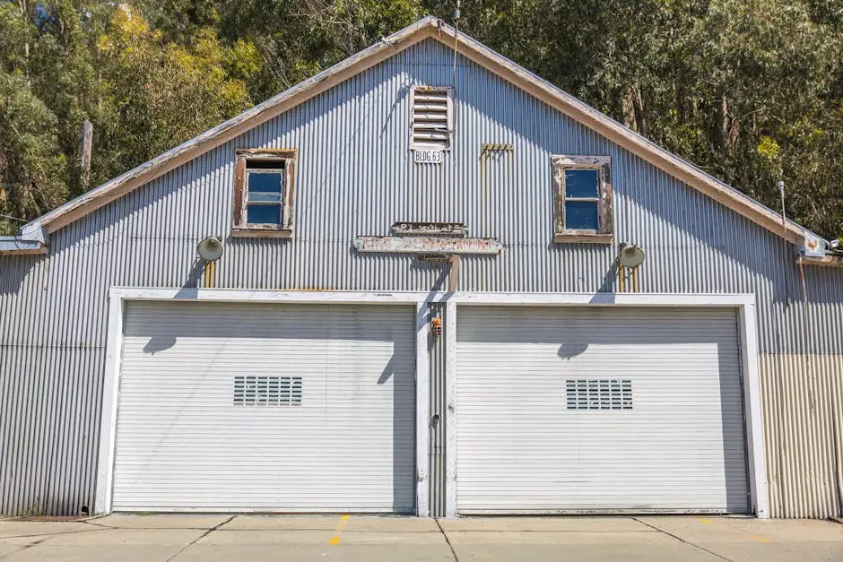 A sunlit vintage metal garage with double doors and rustic charm amidst trees.