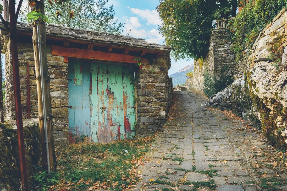 Charming walkway with stone walls and a rustic wooden door, perfect for travel and architecture inspiration.
