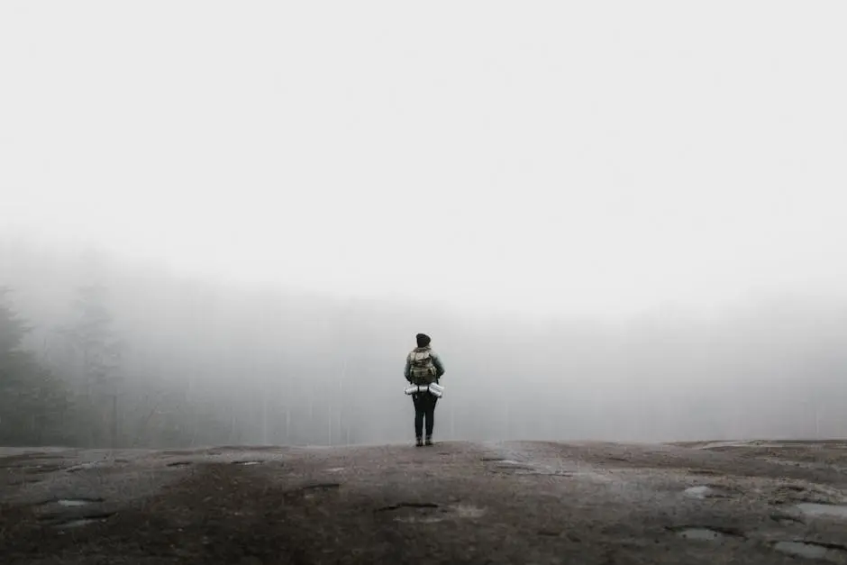 A solitary hiker on a misty mountain path in North Carolina, surrounded by foggy woods.