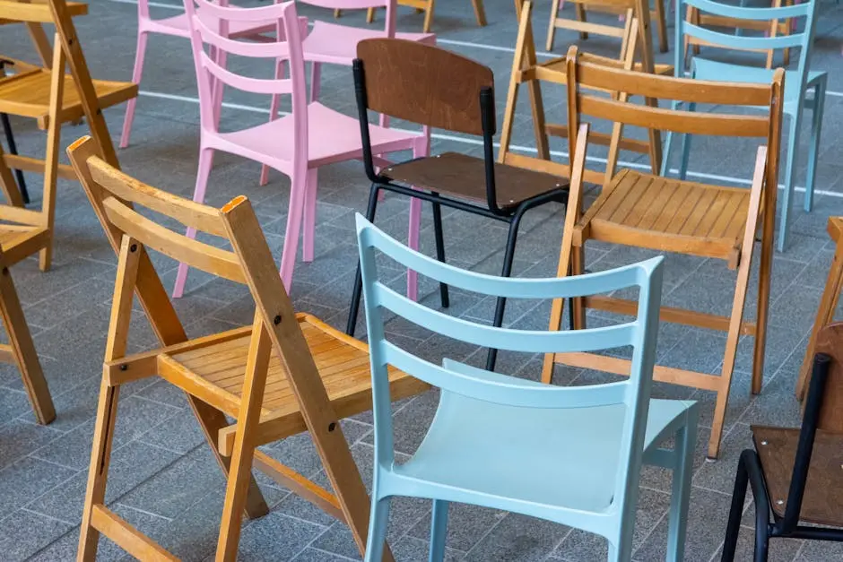 A diverse collection of colorful folding chairs arranged randomly in an outdoor setting.