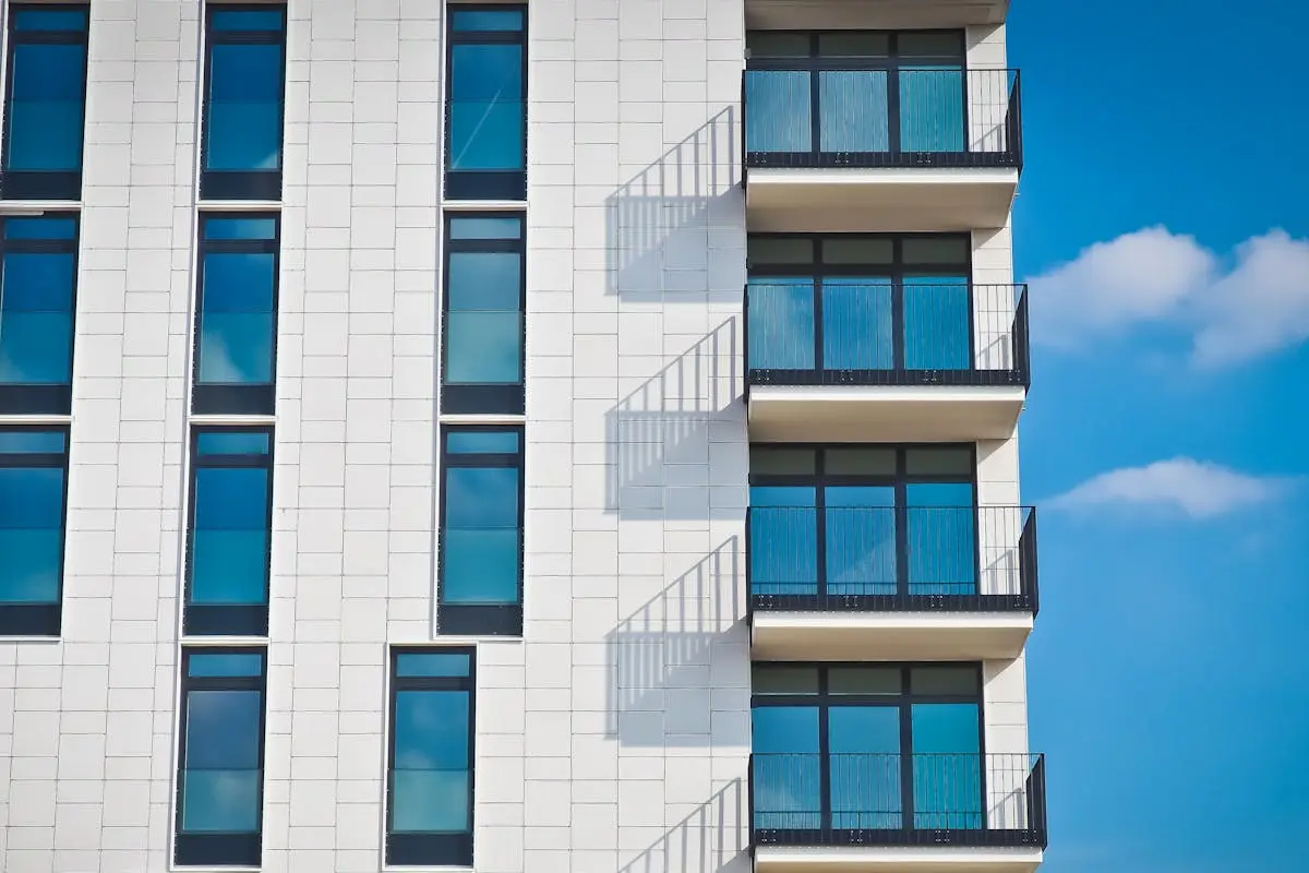 Contemporary urban apartment building with framed glass windows against clear blue sky.