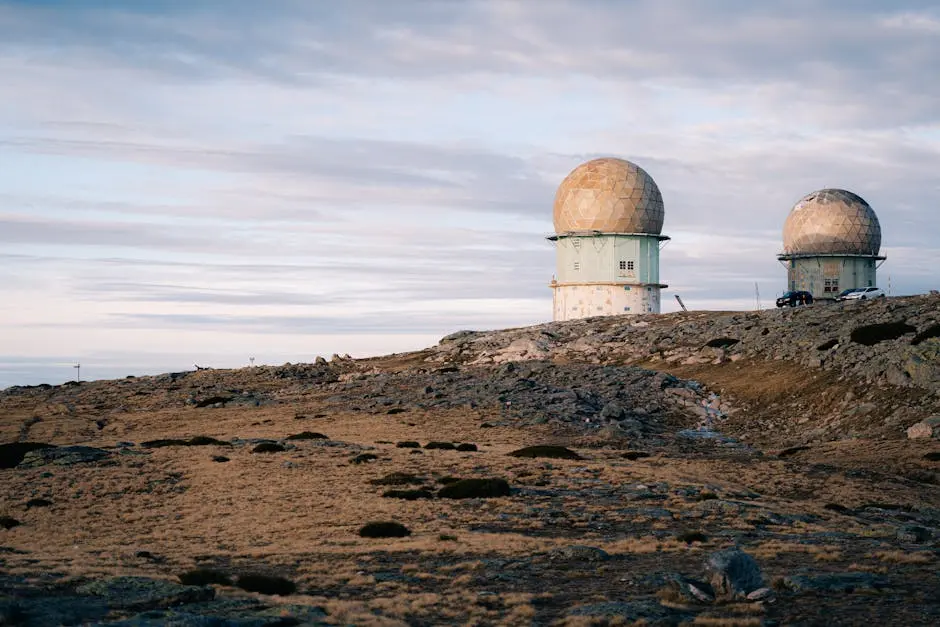 Two radar domes on a rocky landscape under a cloudy twilight sky, symbolizing technology and isolation.