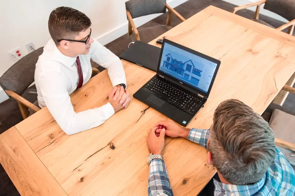 Professionals discuss architectural design on a laptop in a modern office setting.