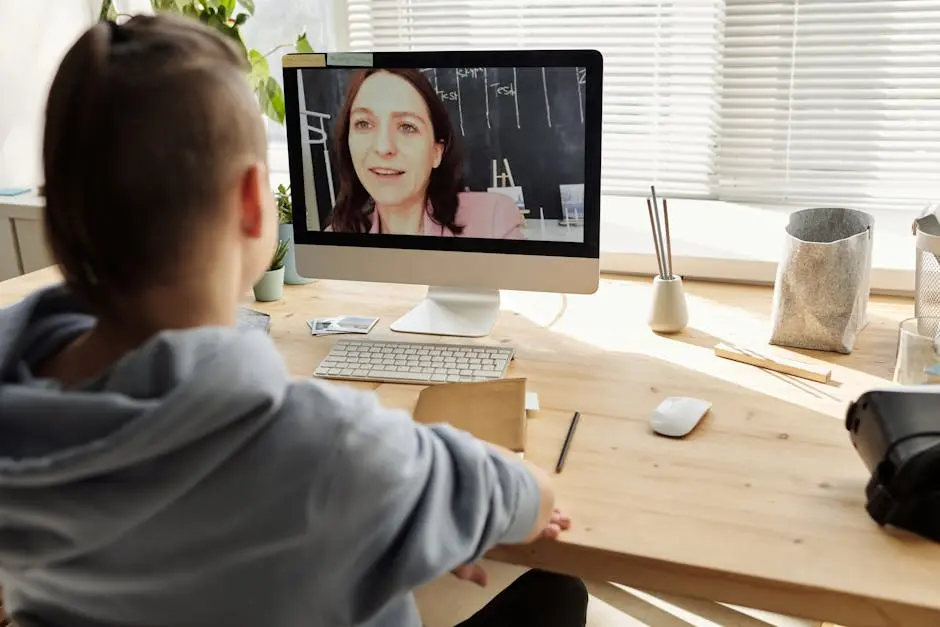 Teenager participating in a virtual classroom setting while seated at a desk at home.