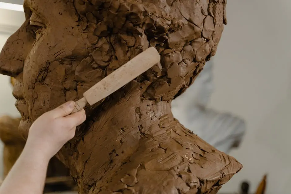 Close-up of a sculptor shaping a clay bust, highlighting artistic craftsmanship.