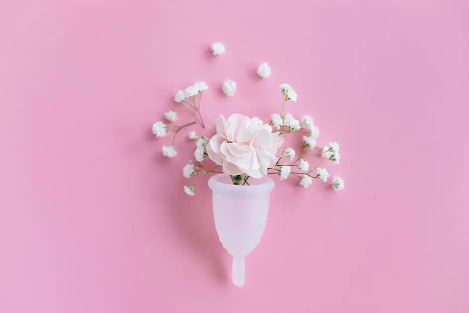 A menstrual cup filled with delicate flowers on a pink background, symbolizing feminine care and eco-friendly solutions.