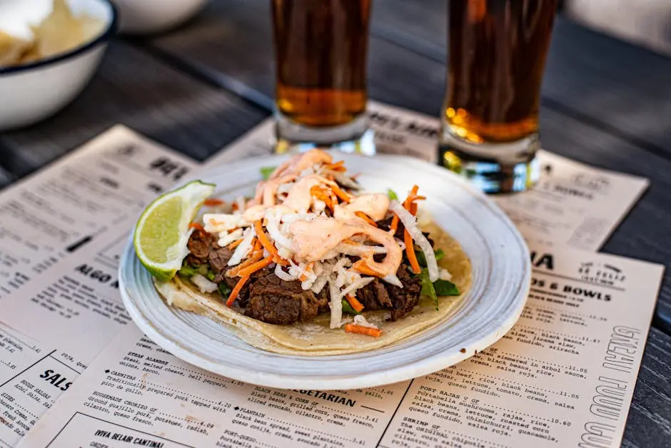 A delicious taco with fresh lime paired with craft beer on a restaurant table.