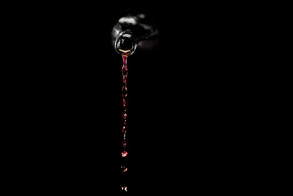 Red wine elegantly pouring from a bottle against a black background, showcasing liquid motion and luxury.