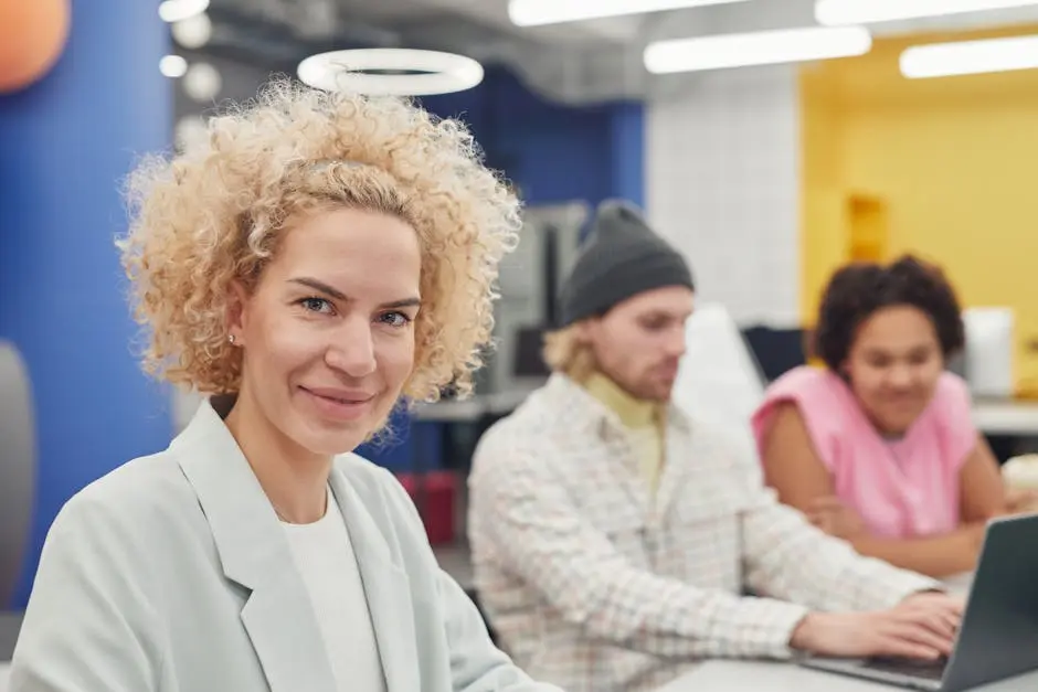 Smiling curly-haired woman leading a multi-ethnic team in a bright office.