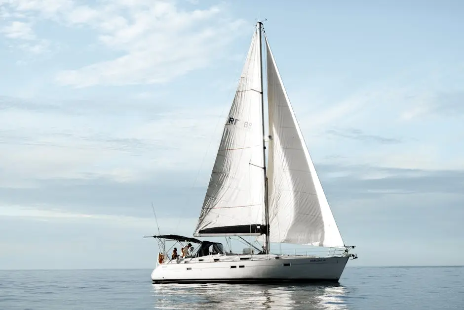 A peaceful sailboat journey on calm waters with clear skies and white clouds.