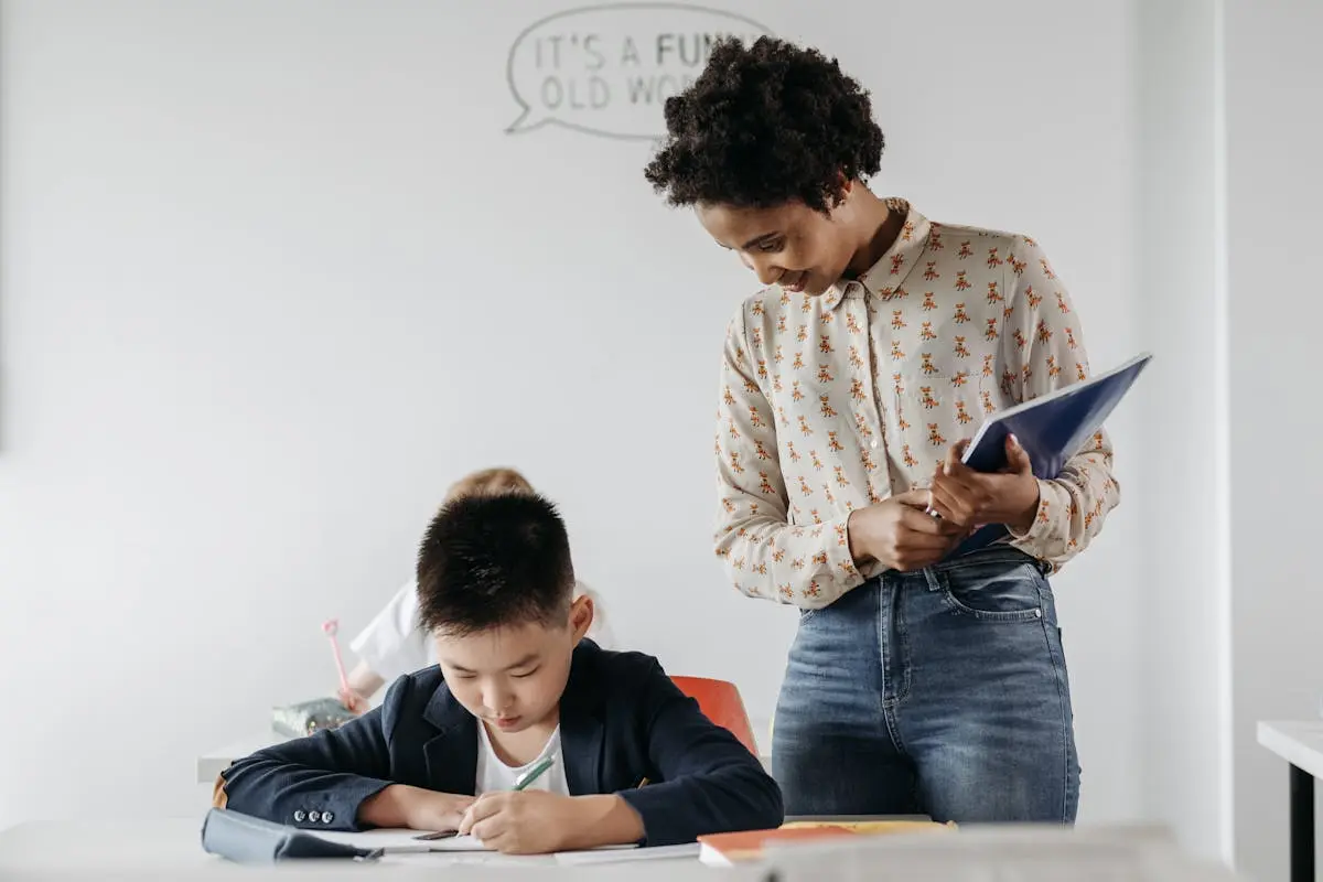 A teacher guides a student in a classroom, fostering an environment of learning and support.