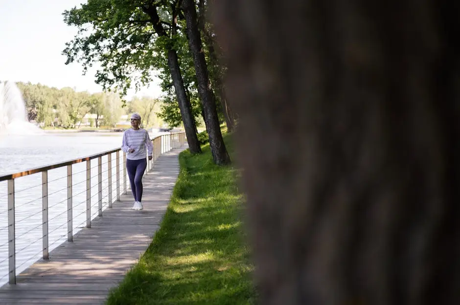 A senior woman enjoys a healthy walk on a lakeside boardwalk on a sunny day.