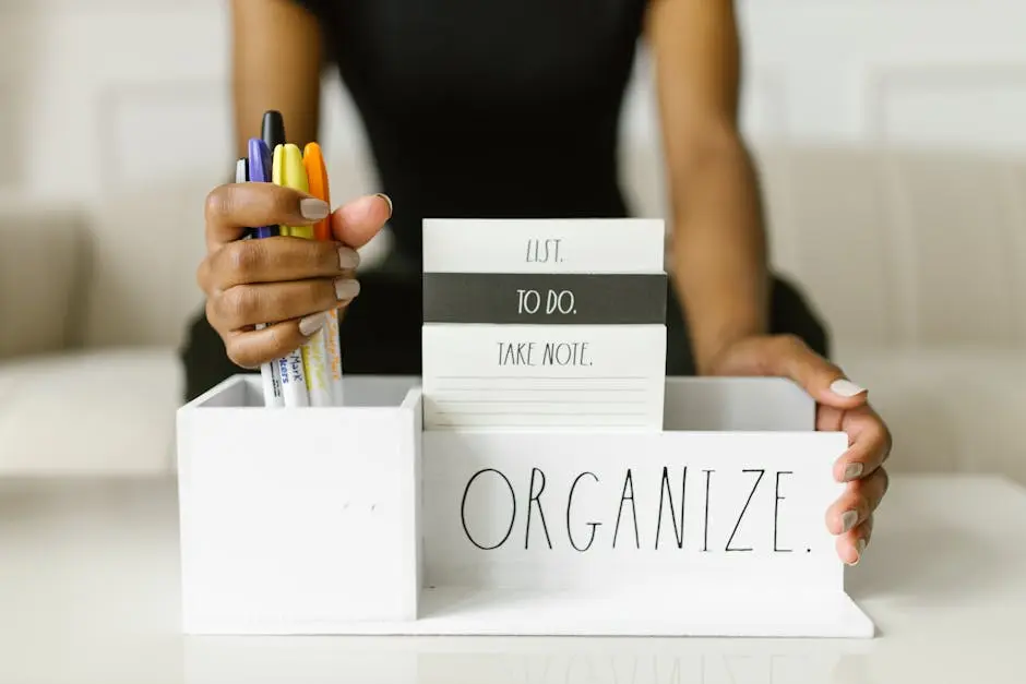 Close-up of hands organizing pens and notes in a white box labeled ‘Organize.’ Perfect for productivity inspiration.