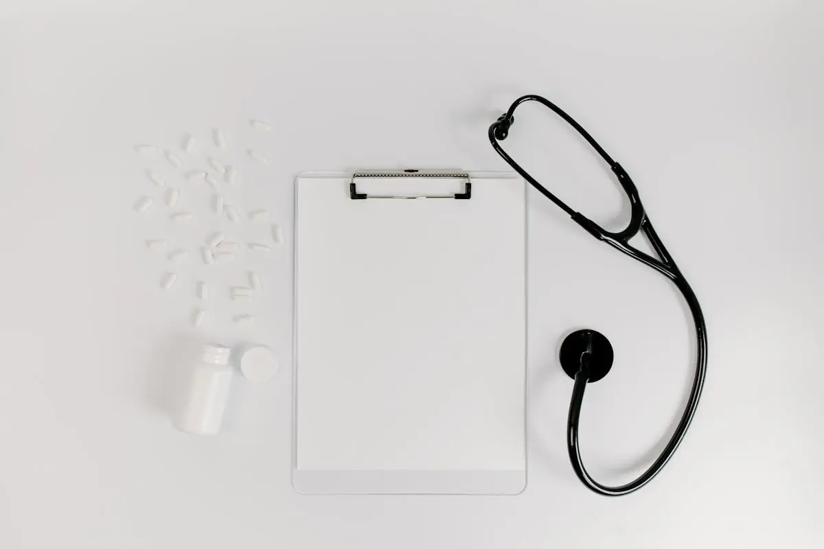 Flat lay of clipboard, pills, and stethoscope for medical use.