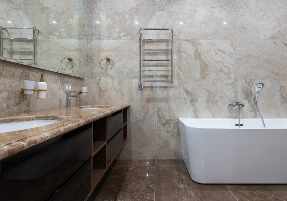 Elegant modern bathroom with marble walls and floors, featuring a bathtub and stylish fixtures.